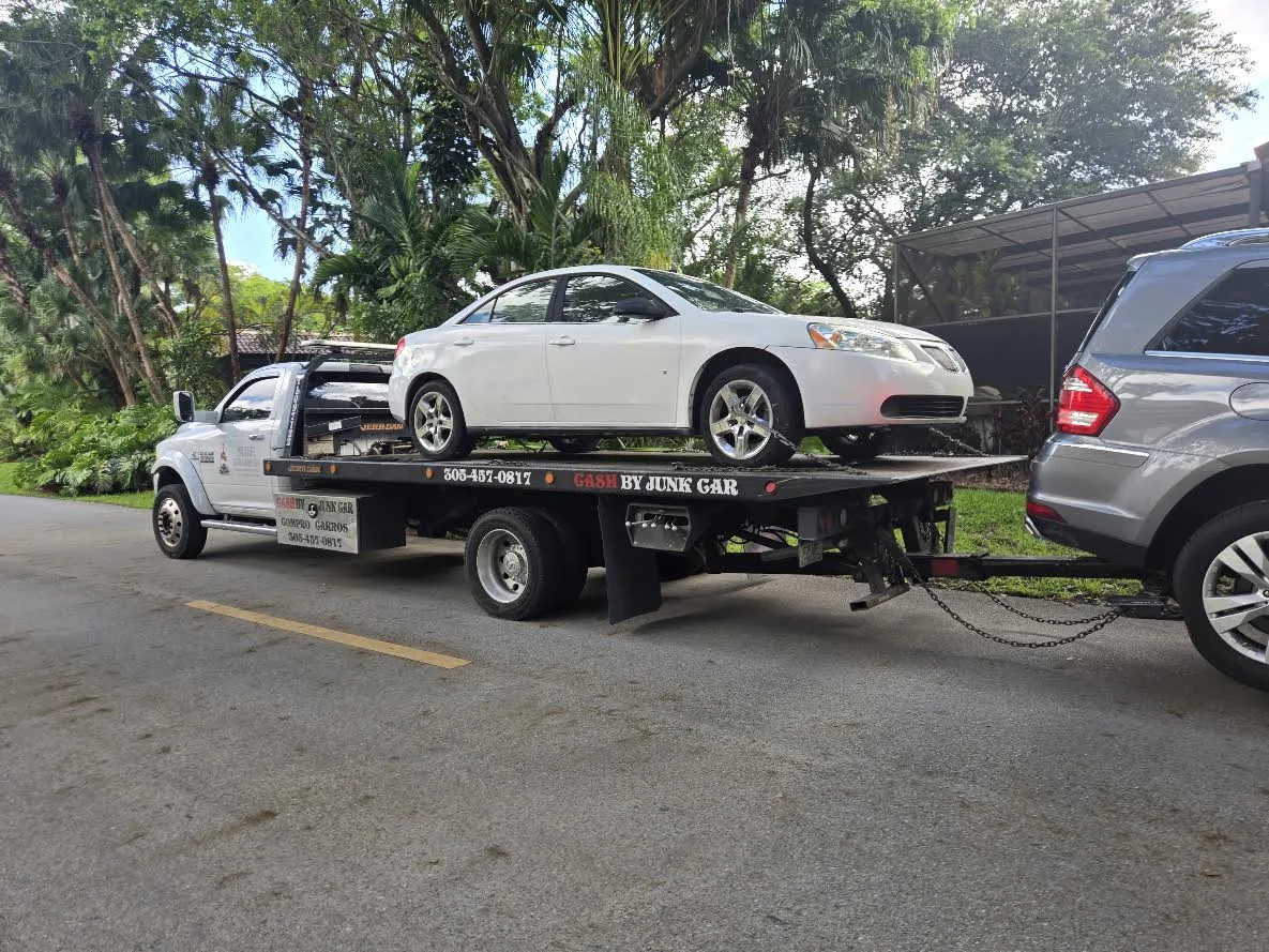 Cash 4 Junk Cars flatbed truck carrying a white Pontiac as a real pickup example for Hallandale Beach