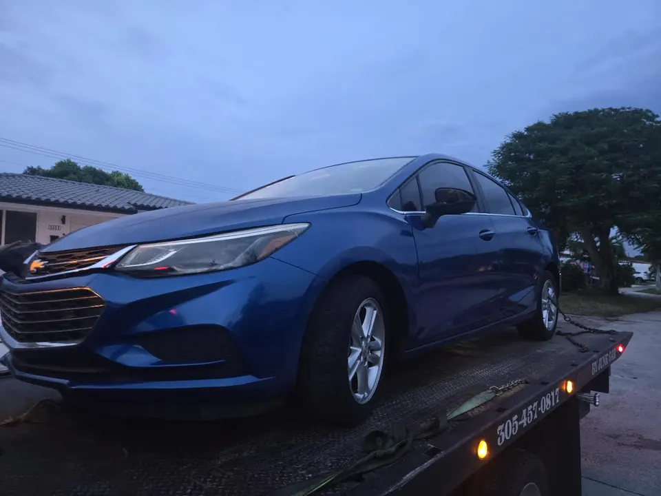 Blue Chevrolet Cruze secured on a Cash 4 Junk Cars Miami flatbed