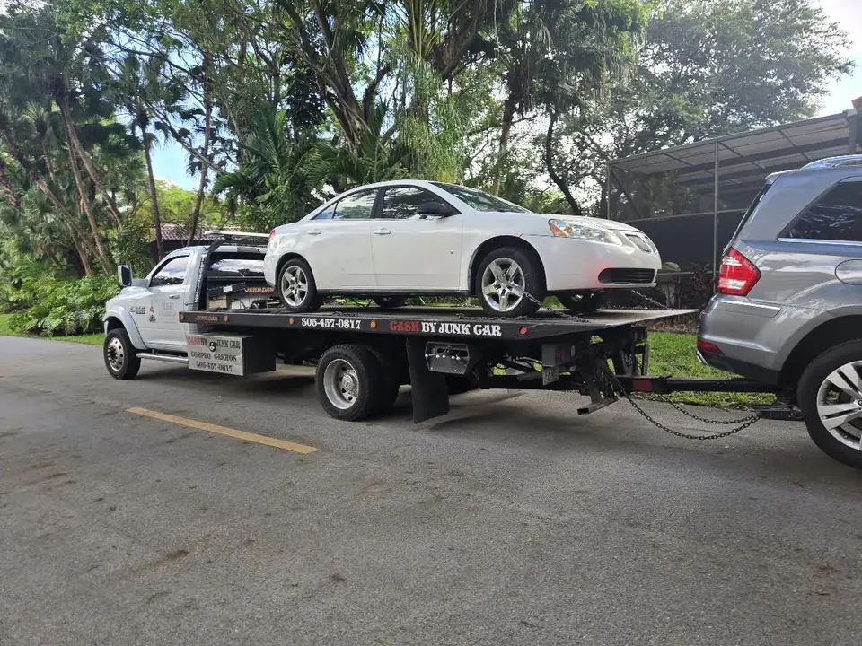 Cash 4 Junk Cars flatbed truck carrying a white Pontiac as a real pickup example for Hallandale Beach
